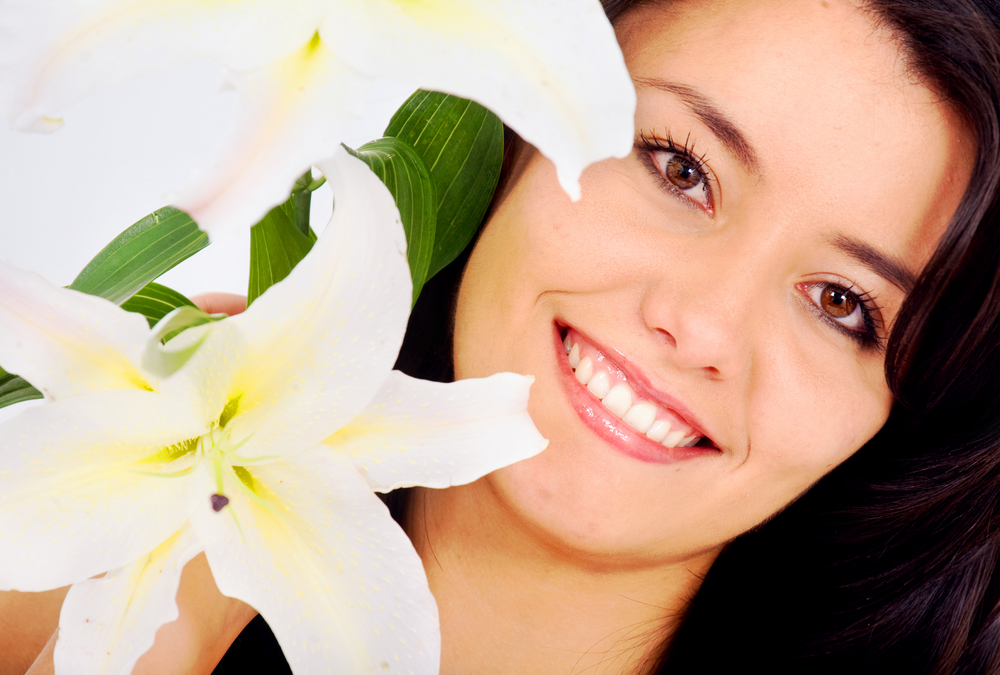 beauty portrait of a girl smiling and holding white flowers by her face